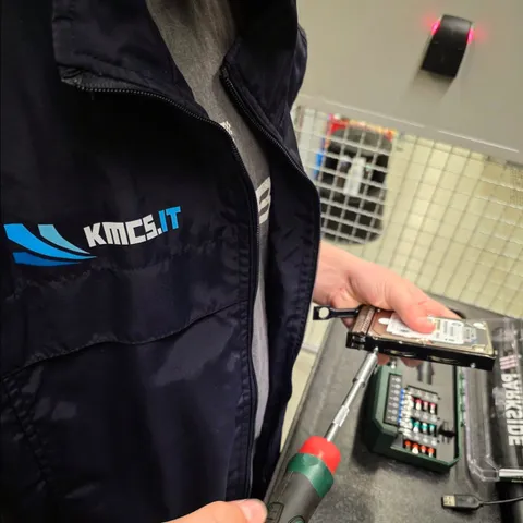KMCS.it technician in branded jacket servicing a hard drive